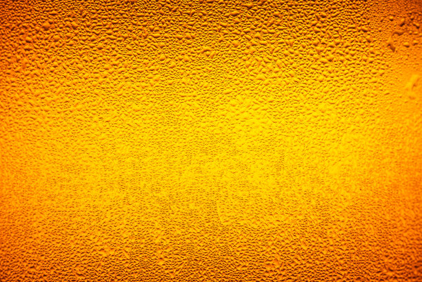 宏观啤酒饮料，水滴背景，近距离滴冰冷品脱啤酒-冷凝。背景是清晰的，强调在金黄色的背景上的水滴。图片下载