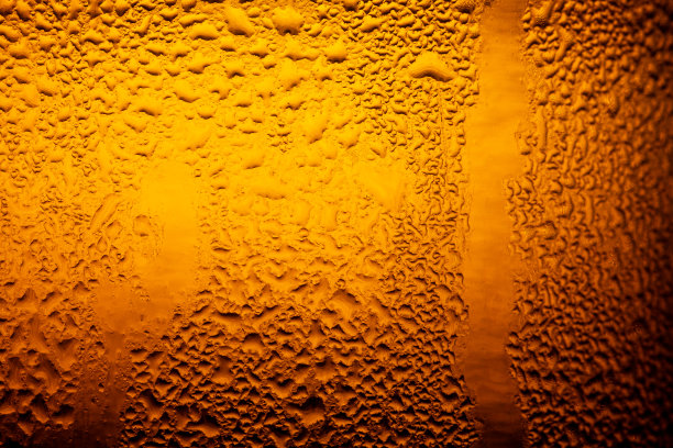 宏观啤酒饮料，水滴背景，近距离滴冰冷品脱啤酒-冷凝。背景是清晰的，强调在金黄色的背景上的水滴。图片下载