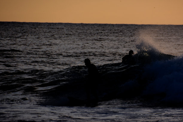 日落时在平静的海面上冲浪图片下载