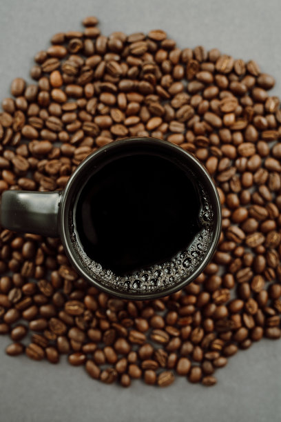 黑咖啡在杯子休息在一堆灰色背景上的咖啡豆图片下载