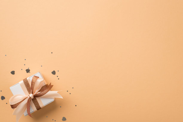 俯视图照片的圣瓦伦丁节装饰白色礼品盒与发光的棕色和浅米色丝带蝴蝶结银色心形纸屑和亮片在孤立的米色背景与空白空间图片下载