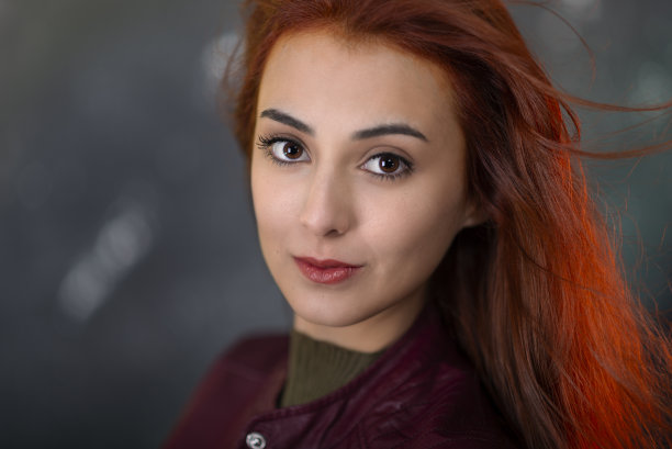 身穿外套的红头发年轻女孩对着镜头微笑。图片下载