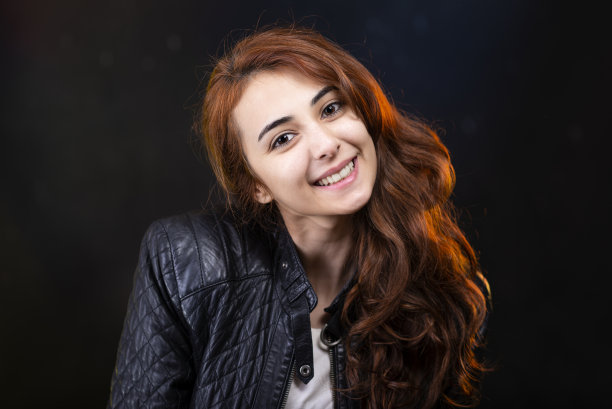 身穿外套的红头发年轻女孩对着镜头微笑。图片下载