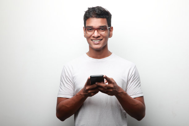 微笑的印度裔年轻人手里拿着手机图片下载