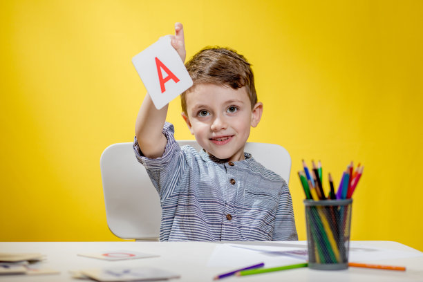 早上开学前，一个快乐微笑的学龄前小男孩在家里写作业。少儿英语学习图片下载