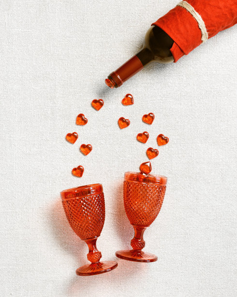 情人节的背景为2月14日，心从酒瓶红酒落在酒杯布纹理的桌子上，复制空间，平铺。浪漫的爱情概念，简约的风格图片下载