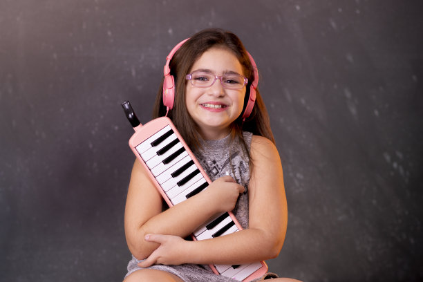 小女孩在深色背景前坐在复古咖啡桌旁，演奏乐器图片下载