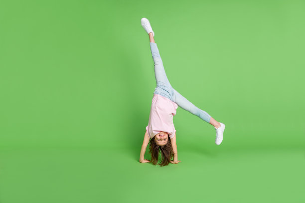 全身照片的小女孩站在手杂技运动训练孤立在绿色的背景图片下载