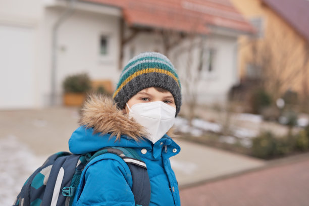 一个戴着医用口罩上学的男孩。孩子背包背包。学生在寒冷的秋冬日子穿着暖和的衣服。冠状病毒大流行期间的封锁和隔离时间图片下载