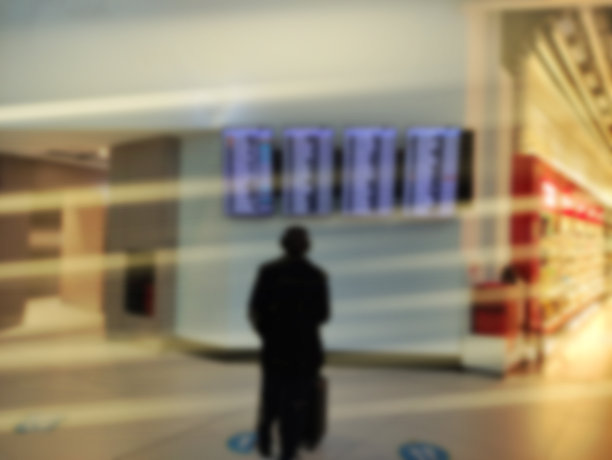 一个男人正在看时刻表。模糊的大厅。图片下载