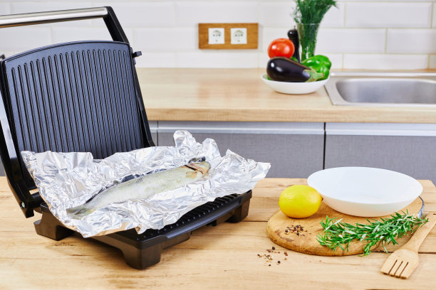 新鲜的海鱼可以煮了。厨房桌上的柠檬鱼和电烤架。健康的饮食习惯。图片下载