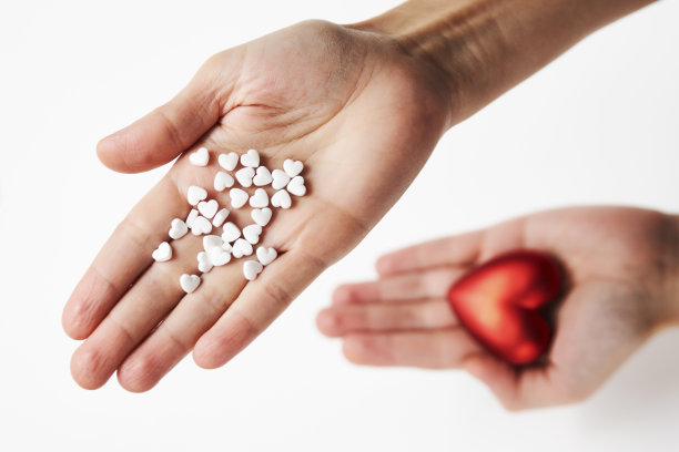 手拿红心和药丸，特写镜头图片下载
