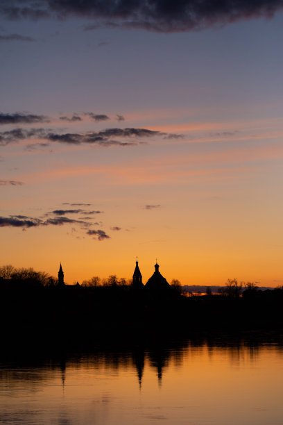 第聂伯河上的日落。美丽的橘色多云的天空，城市和教堂的剪影映在河里。愉快的春天照片在Rechytsa，白俄罗斯图片下载