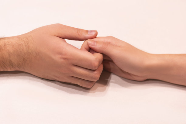 近距离的美国爱的年轻夫妇牵手在一个白色背景的桌子拷贝空间图片下载