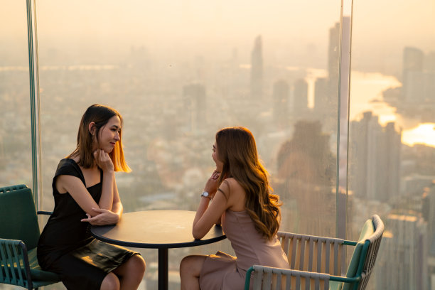亚洲女性朋友在夏日夕阳下在摩天大楼的屋顶餐厅聚会。图片下载