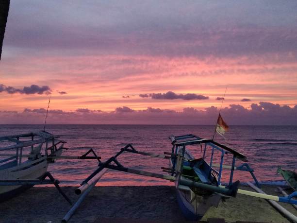 印度尼西亚龙目岛，海滩上传统渔船的粉红色日落图片下载