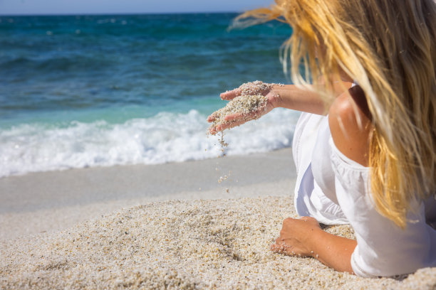 在意大利撒丁岛的海滩上，女人的手在玩沙。图片下载