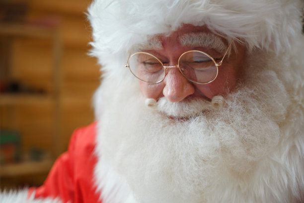一张圣诞老人的肖像照，戴着一副圆眼镜，微笑着往下看图片下载
