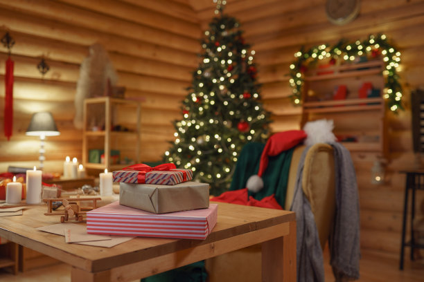 圣诞老人办公室温馨的圣诞室内，装饰着圣诞树，扶手椅上放着圣诞老人的帽子，桌子上放着圣诞老人的物品和圣诞礼物，我们看到房间里充满了温暖的灯光图片下载