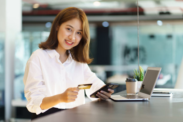 快乐乐观的年轻女商人拿着信用卡和电话。图片下载