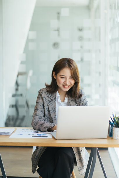 亚洲女性在笔记本电脑上工作，带着笔记本电脑的概念在办公室工作，年轻的亚洲女性用笔记本电脑开始创业。图片下载