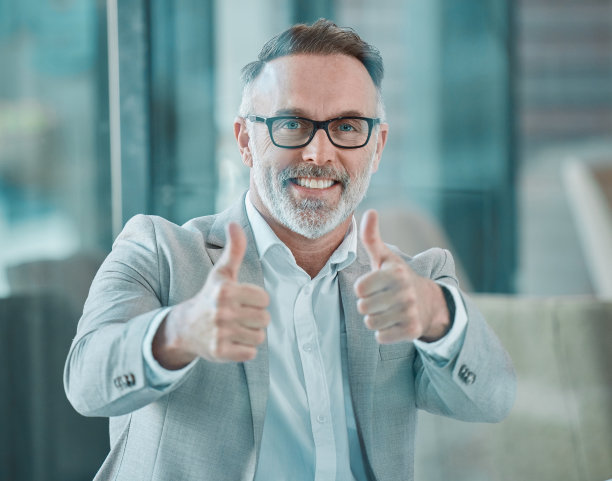 一个成熟的商人在工作时竖起大拇指的镜头图片下载