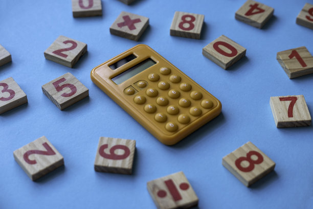 计算器和一个木制的数字和数学符号在蓝色的背景。图片下载
