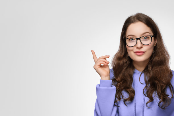 一个留着长发，戴着眼镜，面带微笑的少女。女孩穿着一件紫色的超大号运动衫，向上指着。图片下载