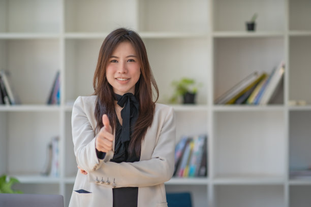在办公室里，亚洲女商人微笑着举起手来，这是一个好兆头图片下载