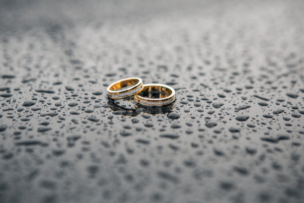 两枚金色的结婚戒指衬着光滑的黑色金属图片下载