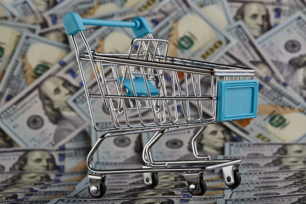 空的购物车压在一堆百元美钞上图片下载