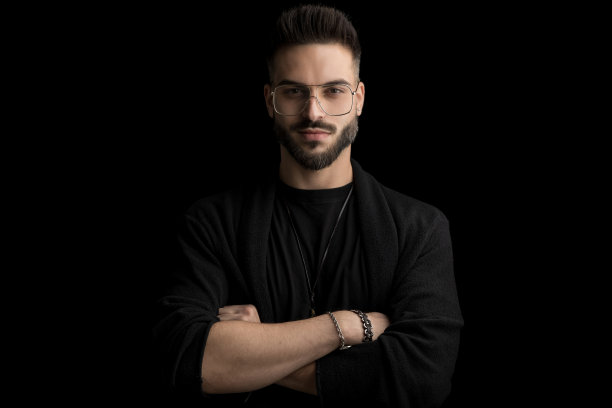 快乐的没刮胡子的年轻人，手臂交叉戴着眼镜，面带微笑图片下载