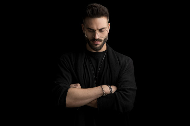 戏剧性的没刮胡子的年轻人垂下眼睛，交叉双臂图片下载