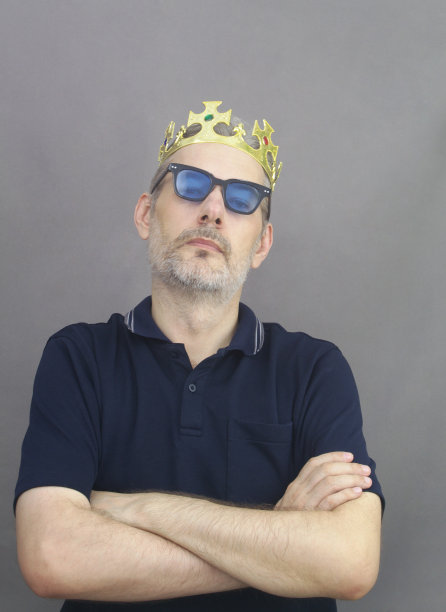 中年男子，灰白头发，留着胡子，戴着蓝眼镜，戴着金王冠。图片下载