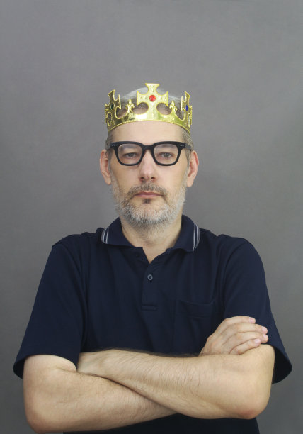 国王——中年男子，灰白头发，留着胡子，戴着眼镜，头上戴着金色的国王王冠图片下载