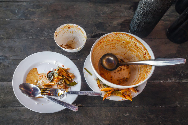 俯视图一个空的白色盘子与一些红酱脏的痕迹，绿色蔬菜与勺子和叉子设置在木制桌子上的复制空间图片下载