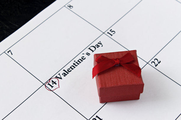 日历页上有红心和礼物，2月14日，黑色背景的情人节。情人节卡片图片下载