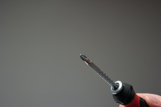 用人的手转动螺丝刀。近景工作室拍摄，孤立的灰色背景图片下载