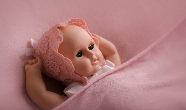 婴儿玩偶玩具照片覆盖在一个新生的风格。包裹在粉红色羊毛织物和花边帽子图片下载