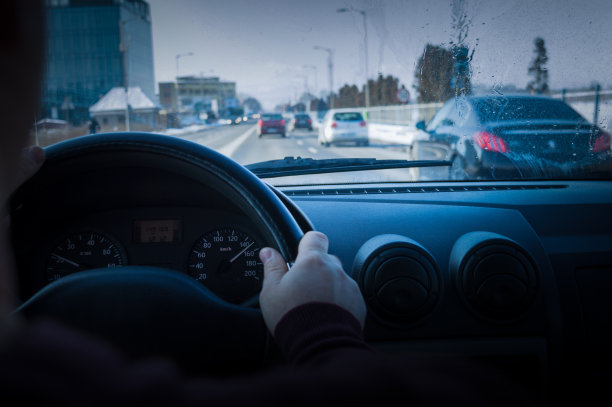 一个不认识的司机正在城市里高速行驶。驾驶员的手握着车辆的方向盘。图片下载
