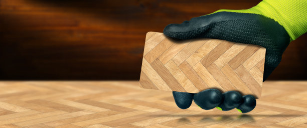 戴着手套的手拿着人字形木地板样品图片下载