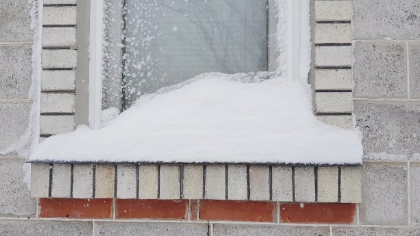 窗户和窗台上覆盖着雪，小雪堆在窗台上。图片下载