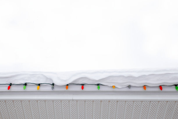 屋顶上厚厚的积雪覆盖了圣诞彩灯图片下载