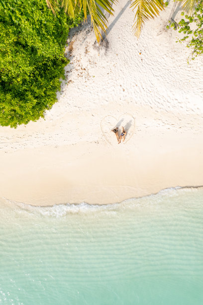 夫妇坐在心形画在海滩上图片下载