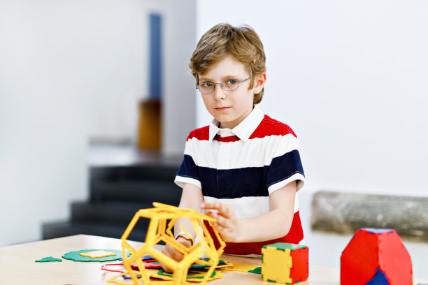 快乐的小男孩戴着眼镜，在建筑和创造几何图形，学习数学和几何的乐趣图片下载