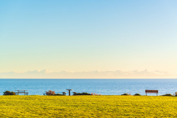 马斯林海滩海滨壮观的景色与野餐桌和日落时的长椅图片下载