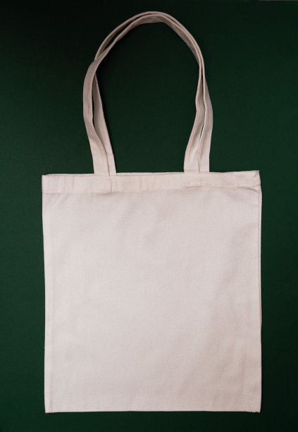 模拟环保米色或白色帆布棉织物手提袋上深绿色的背景。购物袋模型空白模板。可重复使用的杂货和购物袋图片下载