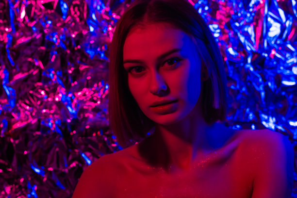 一个美丽的女孩的肖像在紫色，粉红色和蓝色的霓虹灯。年轻女子在未来的样子。图片下载