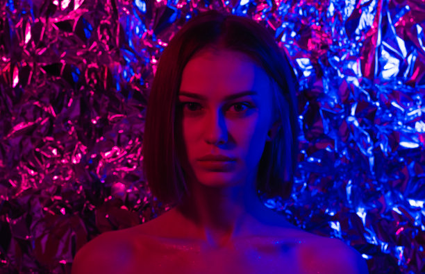 一个美丽的女孩的肖像在紫色，粉红色和蓝色的霓虹灯。年轻女子在未来的样子。图片下载