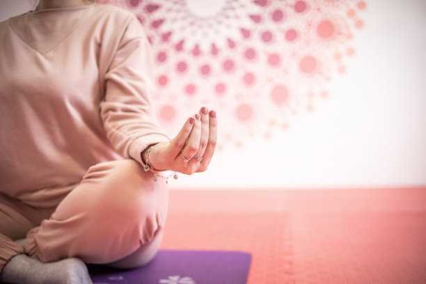 一位穿着粉红色运动服的年轻女子正在练习瑜伽图片下载